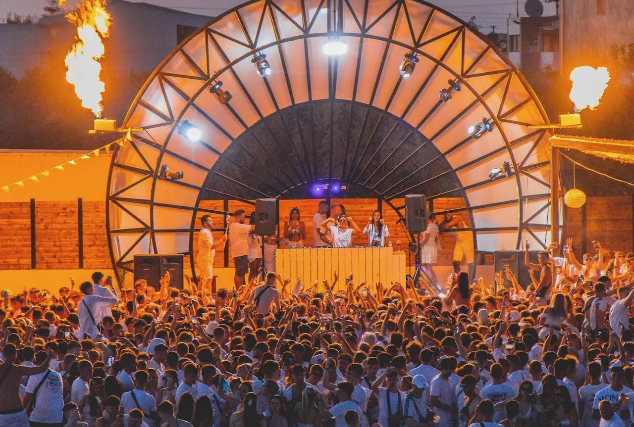 Outdoor event with a large crowd and stage setup at night.